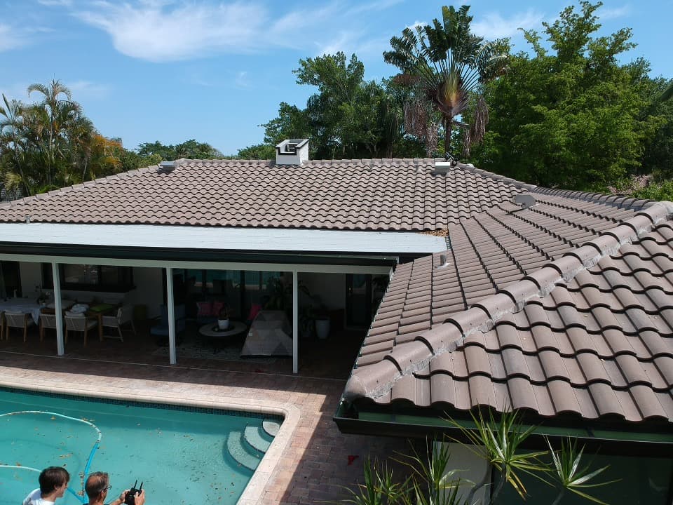Brown tile roof house overlooking a swimming pool and a covered patio area with furniture.
